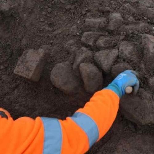 Archaeologist excavating a rubble wall