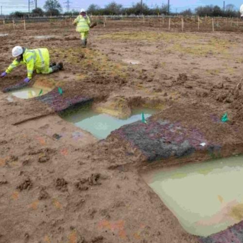 Archaeologist excavating part of a roundhouse on the A428