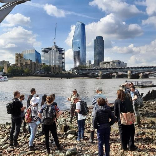 People on the Thames foreshore under the Millennium Bridge.