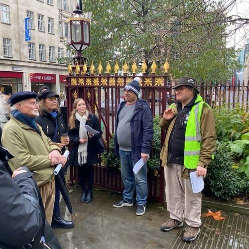 A group of people stood on a London pavement listening to walk guides. Josh and Will in full flow outside St Leonard’s Shoreditch.