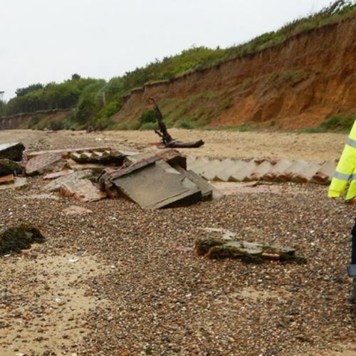 Archaeologist walking on a beach filled with the remains of concrete structures