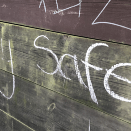 Wooden board with chalk graffiti reading "stay safe"