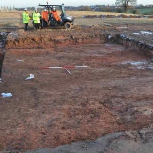Archaeologists standing by an open trench